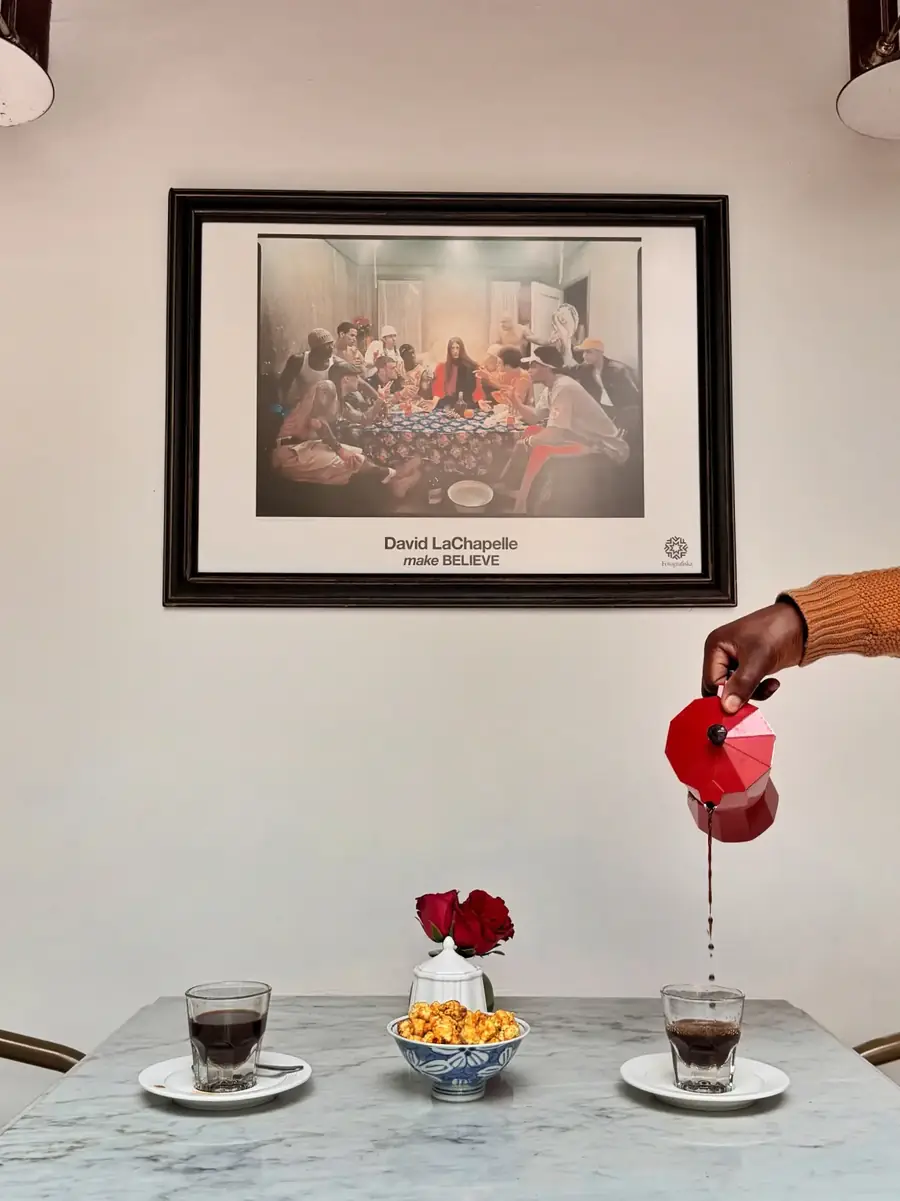 Coffee poured from a red pot beneath a framed print